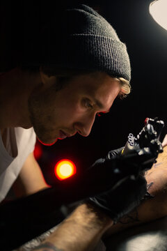Focused artist making tattoo on client's skin