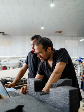 Mechanics using computer in hangar during aircraft maintenance