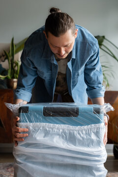 Man unpacking brand new suitcase at home