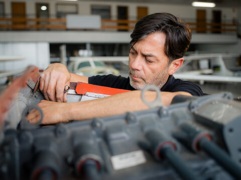 Mechanic Works on Aircraft Engine in Workshop During the Day