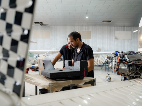 Focused mechanics using computer at hangar while working