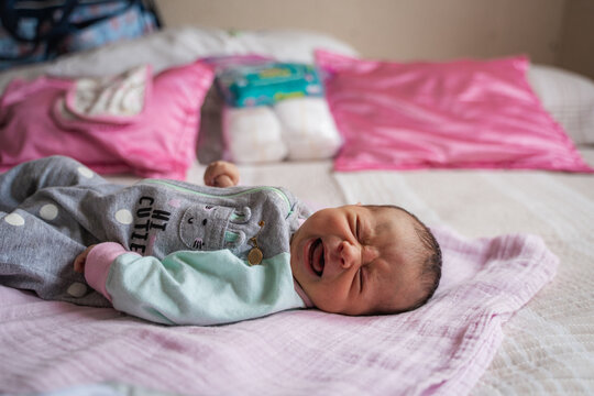 Newborn baby crying on bed feeling upset and distressed