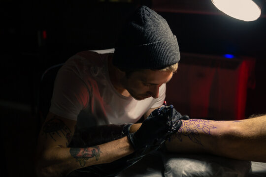 Man creating tattoo on client's leg