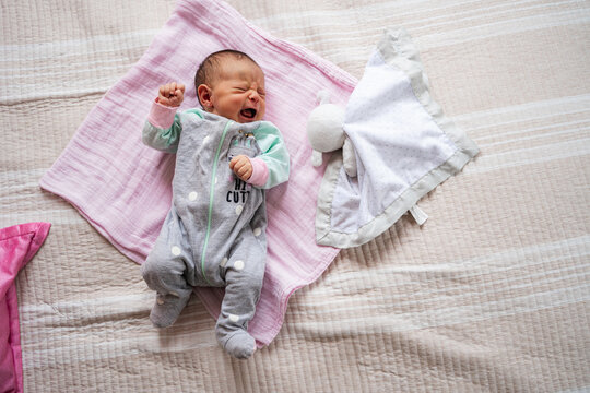 Newborn infant crying on a soft pink blanket