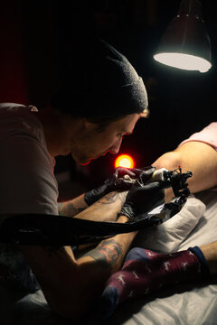 Artist tattooing customer's leg at studio