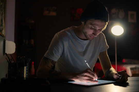 Tattoo artist working on new design at dark studio