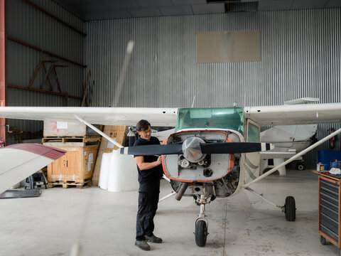 Mechanic Works on Small Plane in Hangar During Daytime Hours