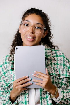 Black female freelancer holding a tablet, smiling at the camera.