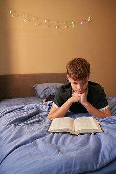 Teen Boy Lying on Bed Reading Book