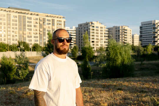 Bold man in bold sunglasses posing outdoors in urban lifestyle scene