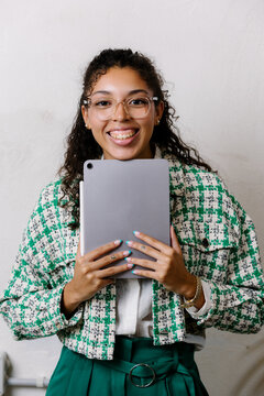 Determined female freelancer holding a tablet with a motivated smile.