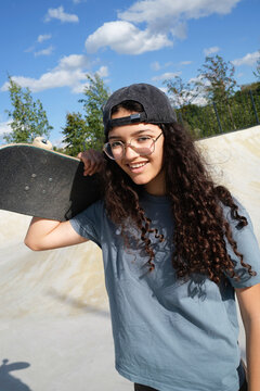 Skateboarder poses at skate park in sunny weather with clear sky