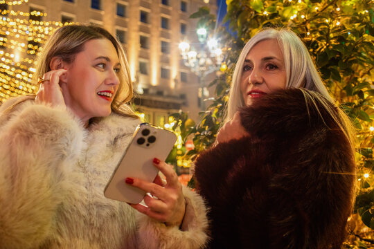Women Chatting Near Holiday Lights in the Evening
