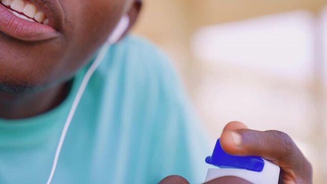 Close up shows hands wearing white earphones while gripping object. focus remains tightly on fingers and blue and white item with soft lighting creating depth of field