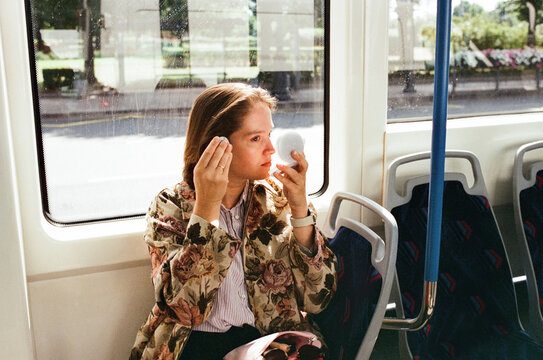 Woman applying makeup on public transport