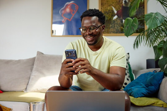 Happy man sits at home, checking his phone