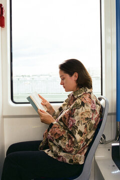 Woman reading a book while sitting on a train