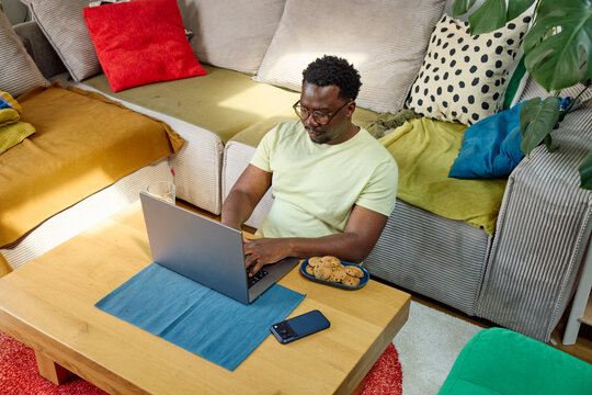 Man sits in the living room, checking his laptop
