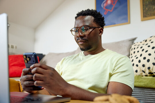 Man sits in the living room, checking his phone