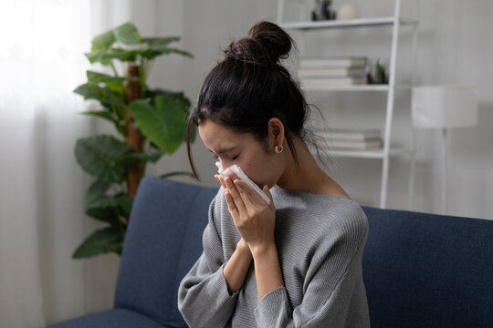 The young woman sat on the sofa in the living room, clutching her chest in obvious discomfort, possibly indicating heartburn. She also had a cough, sore throat, and runny nose.