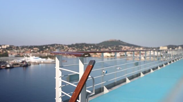 Wooden ship handrails with and blue upper deck against blurred La Seyne sur Mer waterfront