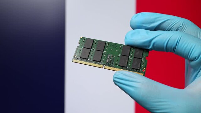 Close up view of hand in blue glove holding RAM memory microchip module. French flag in blurred background. Concept of semiconductor shortage, artificial intelligence development in France.