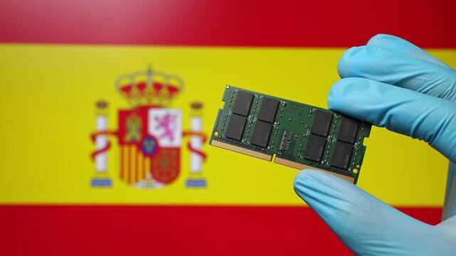 Close up view of hand in blue glove holding RAM memory microchip module. Spanish flag in blurred background. Concept of semiconductor shortage, artificial intelligence development in Spain.