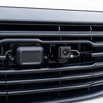 Close-up of dual sensor units behind a car's front grille used for radar and camera based driver assistance, automotive sensor fusion concept