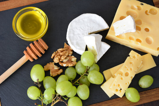 Assorted Cheese, Grapes, Walnuts, and Honey on Slate Board, flat lay
