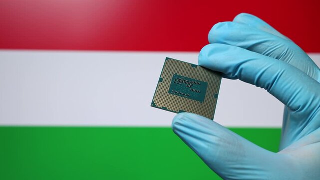 Close up view of hand in blue glove holding CPU microchip. Hungarian flag in blurred background. Concept of semiconductor shortage and artificial intelligence development in Hungary.
