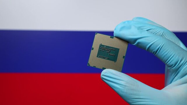 Close up view of hand in blue glove holding CPU microchip. Russian flag in blurred background. Concept of semiconductor shortage and artificial intelligence development in Russia.