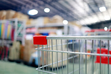 Empty shopping cart inside a large retail store, with blurred shelves and cardboard boxes in the background, shopping, wholesale, retail business and consumer lifestyle © cgdeaw