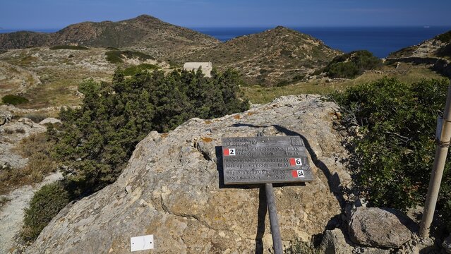 Signpost on rocky ground with a view of hilly coastal landscape, mushroom rocks, mushroom rock, bizarre rocks, rock formation, Skiadi, Kimolos, Cyclades, Greek Islands, Greece