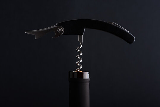 Elegant corkscrew opening dark bottle top in studio lighting with dramatic dark background