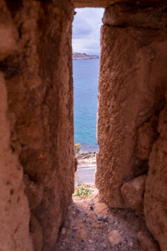 Sea view through narrow arrow slit in stone fortress wall