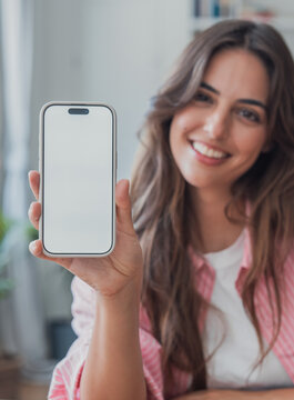 Young woman holds a smartphone mockup with a blank white screen toward the camera. Vertical mobile device offers copy space for app, website, advertising, interface, and communication design.
