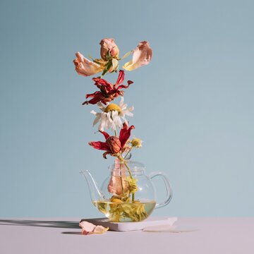 Floating dried rose and chamomile blossoms rising from a clear glass teapot on a lilac surface, ethereal and calm for spa menus and tea packaging