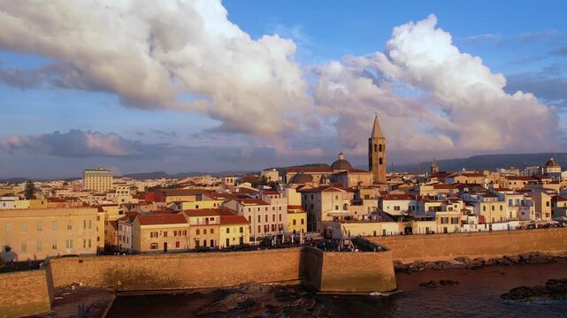 Aerial view of Alghero, Sardinia, showcasing its vibrant coastal scenery, historic buildings, and tranquil waters. Ideal for travel enthusiasts and explorers at sunset.