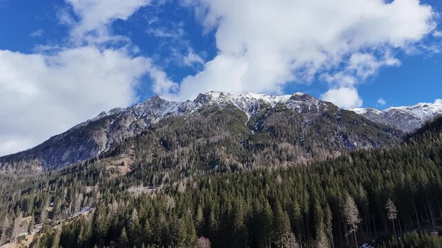 Drone Shot of an Austrian Mountain Landscape in Winter with Rocky Peaks and Forest in Europe.