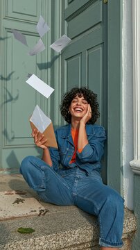 Middle Eastern woman laughing on a stone step while holding a green card application envelope, for immigration law and newcomer campaigns