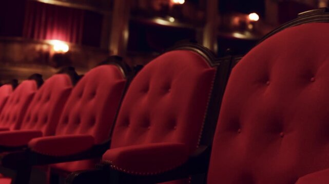 Empty red velvet chairs line the ornate theater, softly lit by vintage lights. The atmosphere buzzes with excitement as guests prepare for a captivating show.