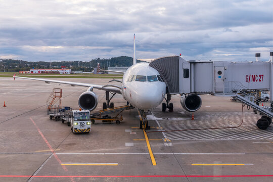Sochi, Russia - October 23, 2025: Boarding a plane through a gate at Sochi Airport. An airplane with the inscription smartavia and a teleport attached to it stands at the airport on a cloudy day