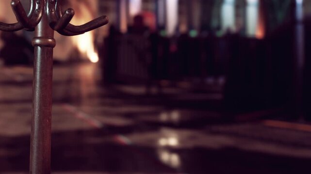 In a bustling city scene during the evening, a coat rack stands still, inviting people to leave their belongings as warm lights illuminate the lively atmosphere around it.
