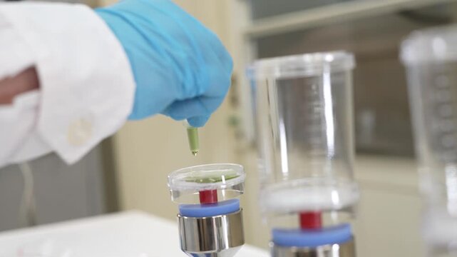 Scientist using sterile forceps to place membrane filter into filter unit on vacuum manifold