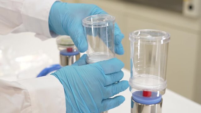 Scientist attaching filter funnel to membrane filter base on stainless steel vacuum manifold