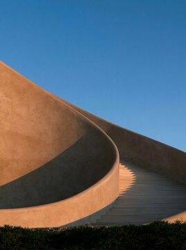 Terracotta curved staircase against a vivid blue sky