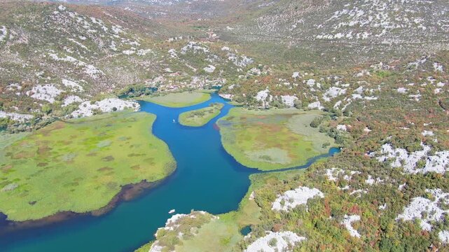 Breathtaking cinematic drone footage flying over the vast pristine waters and lush green mountain shores of Lake Skadar National Park in Montenegro