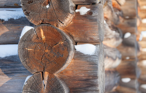 Close-up of weathered wooden log wall with snow