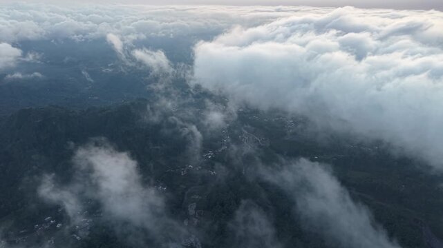 Clouds drift over forested hills. Aerial view shows nature vast, serene beauty. Silent, peaceful at Pronojiwo, Lumajang