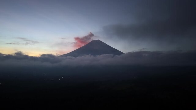 Dramatic Aerial sunrise of Mount Semeru emitting pink ash plume above cloud inversion.